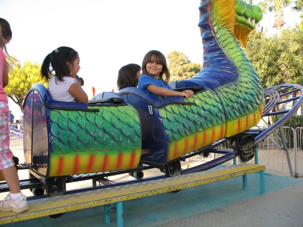 Young children on a dragon themed kiddie rollercoaster