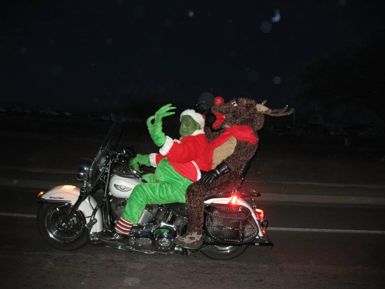 Person dressed up as the Grinch on a motorcycle with a passenger dressed as a Rudolph the red nosed reindeer