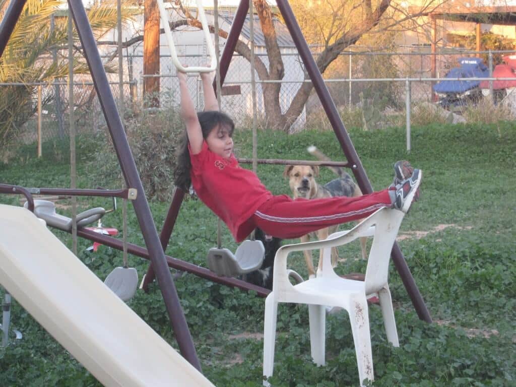 Young child swinging on the trapeze bar of a swing set