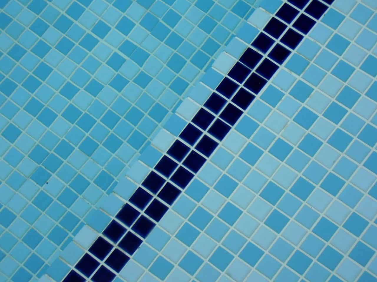 Looking down into an indoor pool at the blue line that separates the shallow and deep end of the pool