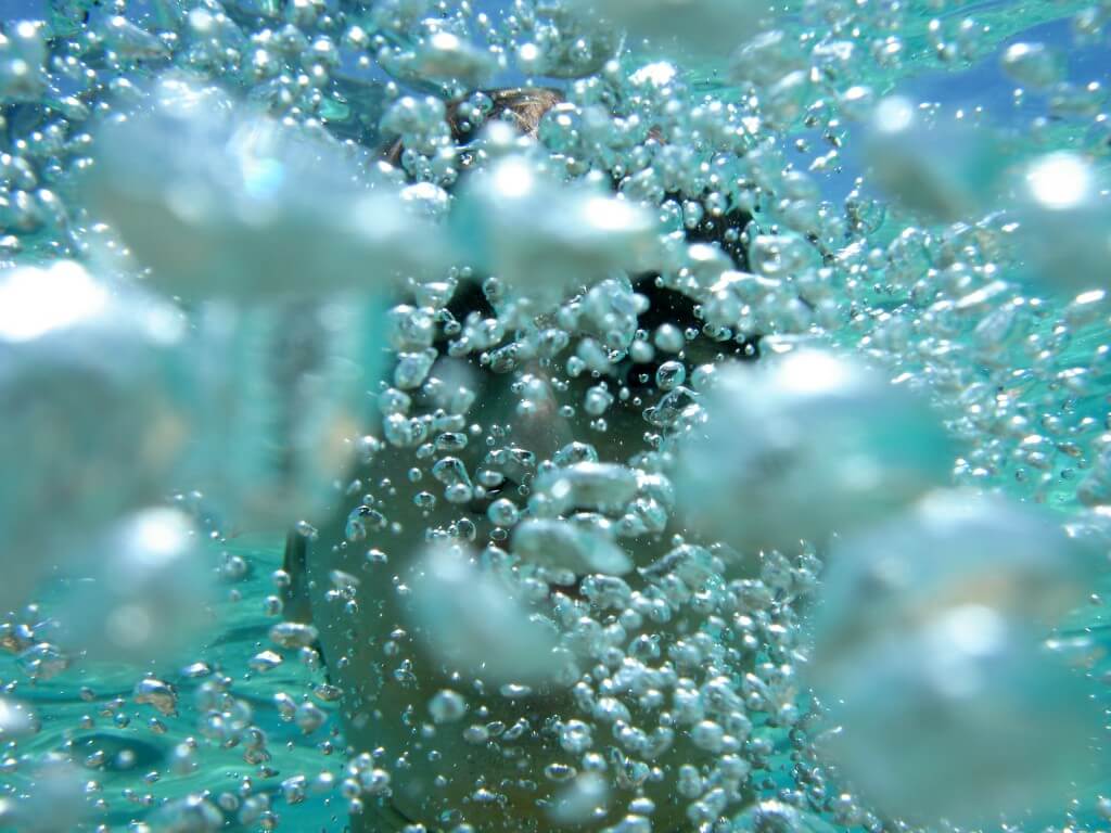 Person underwater surrounded by many bubbles