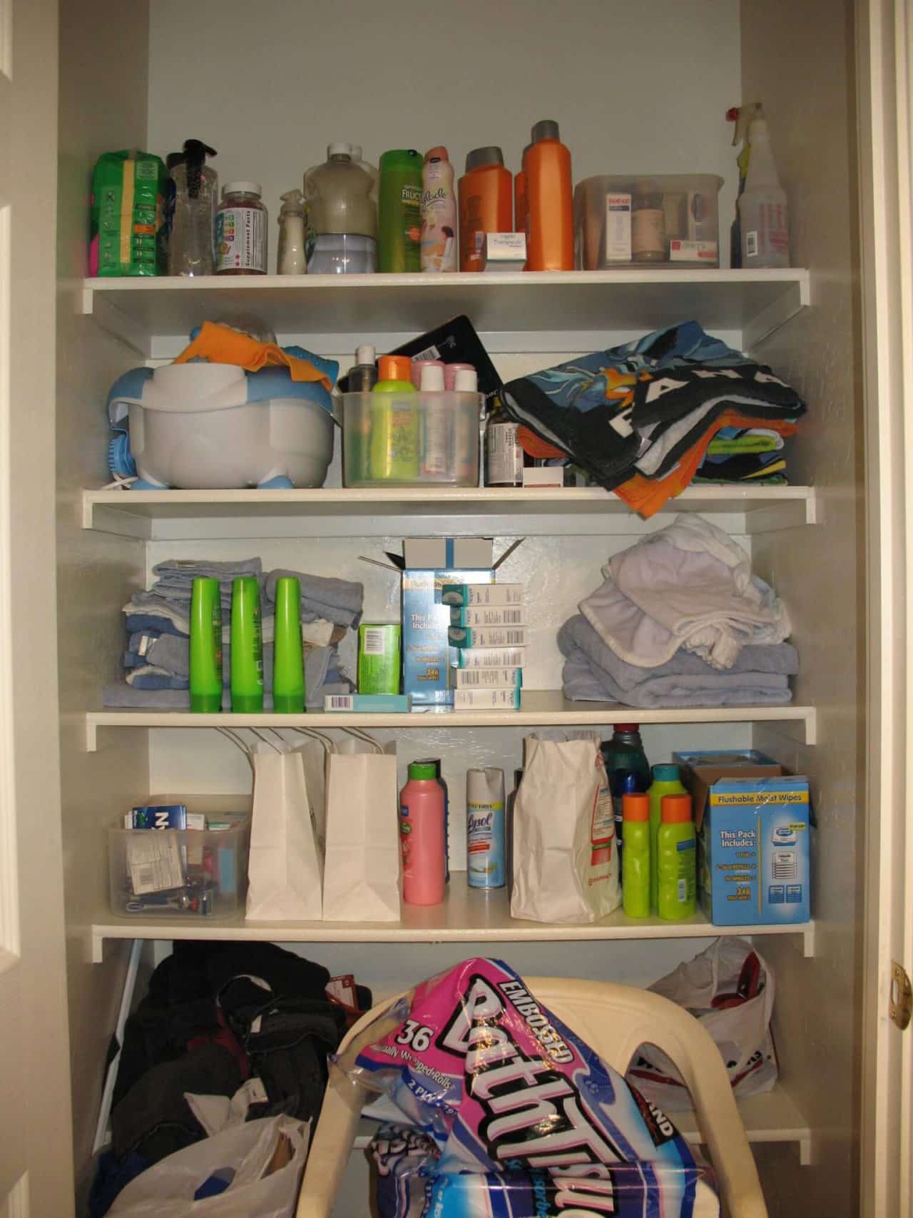 Bathroom closet with items haphazardly on shelves and no organization
