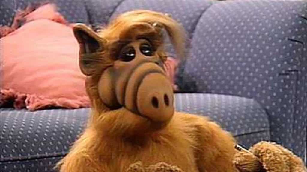 Alf (alien) sitting on the floor next to a couch