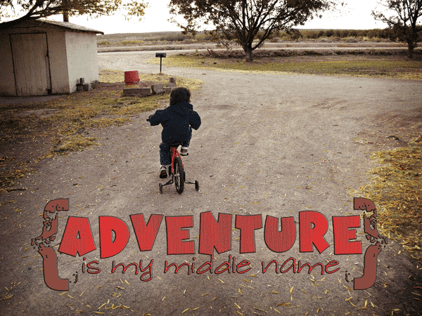 Young child riding a bicycle with training wheels on a dirt driveway