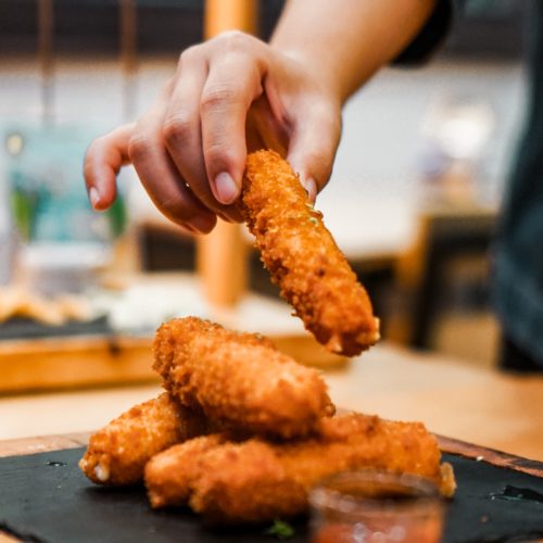 Person dipping steak fingers into cocktail sauce