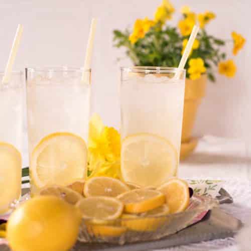 Serving tray with three glasses of lemonade with a slice of lemon inside each glass