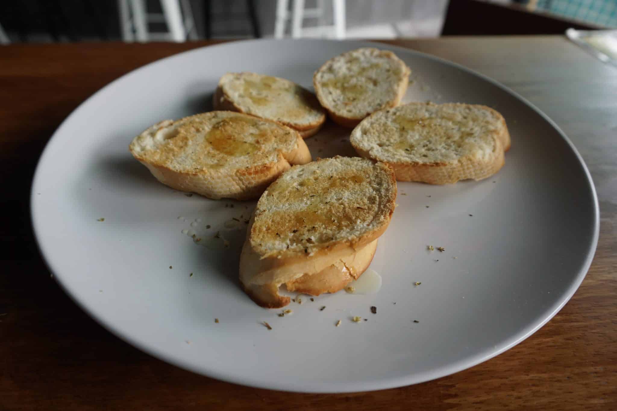 Five slices of rustic garlic bread on a plain white plate