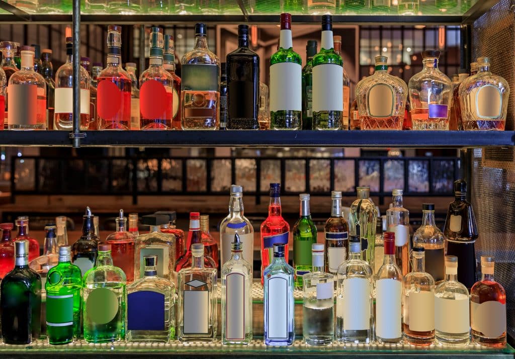 Selection of alcohol bottles on shelves on display in liquor cabinet